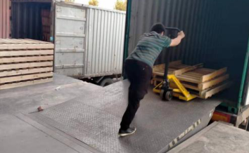 The manual hydraulic transport vehicle enters the interior of the carriage with the help of the cargo platform height adjustment plate